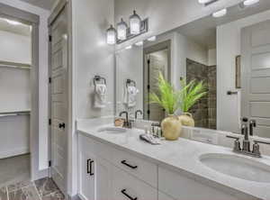 Bathroom with double vanity, walk in shower, and a walk in closet