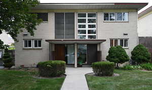 Doorway to property featuring brick siding and a lawn