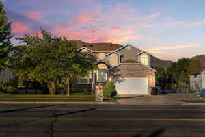 View of front of house with driveway, brick siding, a garage, a mountain view, and a front yard