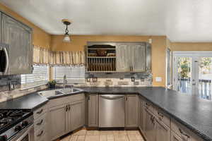 Kitchen featuring dark countertops, decorative light fixtures, tasteful backsplash, stainless steel appliances, and a textured ceiling