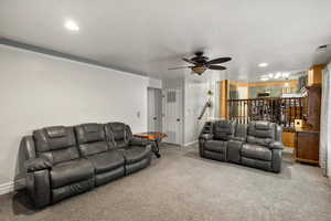 Carpeted living area with ceiling fan and recessed lighting