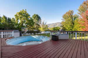 Deck with a mountain view, a fenced backyard, and a shed