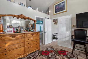 Bedroom with light colored carpet, vaulted ceiling, and a textured ceiling