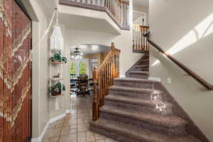 Stairway featuring arched walkways, tile patterned floors, a ceiling fan, and a towering ceiling