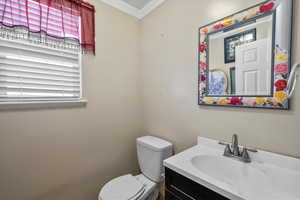 Half bath featuring ornamental molding and vanity