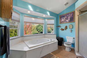 Bathroom featuring light tile patterned floors, a shower stall, a garden tub, vaulted ceiling, and recessed lighting