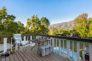Wooden terrace featuring a mountain view, a yard, and view of scattered trees