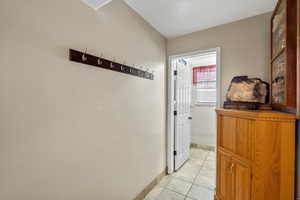 Hallway with light tile patterned floors and baseboards