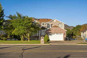 View of front of home with brick siding, concrete driveway, a mountain view, and an attached garage
