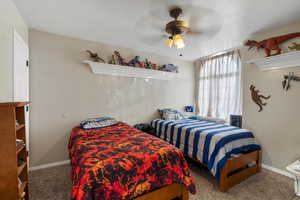 Carpeted bedroom featuring ceiling fan and a textured ceiling