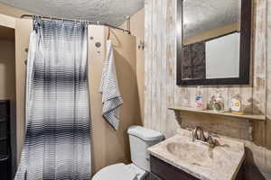 Bathroom featuring a textured ceiling, vanity, and a shower with curtain
