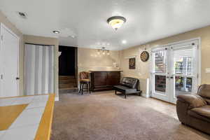 Living area featuring light carpet, light tile patterned floors, a textured ceiling, and a bar
