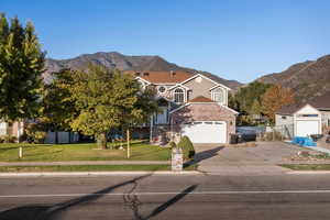 View of front of home featuring a mountain view, a front yard, driveway, and brick siding