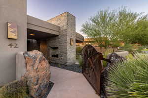 View of property exterior with stone siding, stucco siding, an outdoor stone fireplace, and a patio area