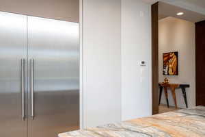 Kitchen featuring stainless steel built in fridge and light stone countertops