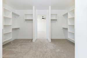 Spacious closet featuring light colored carpet and a ceiling fan