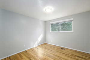 Empty room featuring light wood-style floors and a textured ceiling