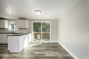 Kitchen with decorative backsplash, dark wood finished floors, white cabinetry, and a peninsula