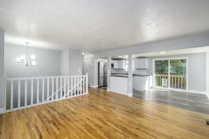 Unfurnished living room with light wood finished floors, a textured ceiling, and a chandelier