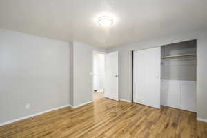 Unfurnished bedroom with a textured ceiling, light wood-type flooring, and a closet
