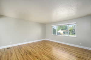Empty room with light wood-type flooring and a textured ceiling