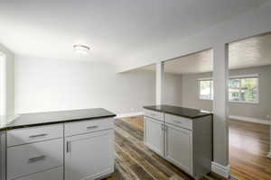 Kitchen with dark stone countertops, dark wood-style flooring, and white cabinetry