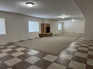 Below grade area with a textured ceiling and a fireplace with raised hearth