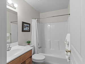 Full bath featuring shower / bath combo, vanity, and a textured ceiling