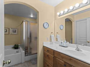 Full bath with vanity, light tile patterned floors, a shower stall, and a bath