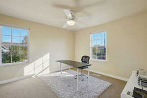Office area with light colored carpet and a ceiling fan