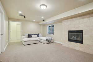 Living area with a glass covered fireplace, recessed lighting, and light colored carpet