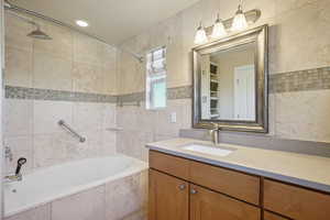 Full bathroom featuring tile walls, vanity, and tiled shower / bath