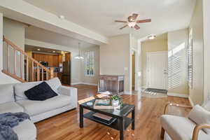 Living area featuring light wood-type flooring, stairway, ceiling fan, and a chandelier