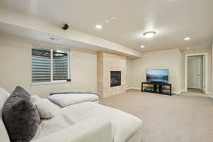 Bedroom with light carpet, a tiled fireplace, and recessed lighting