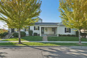 View of front of house with a porch, a front yard, and a shingled roof