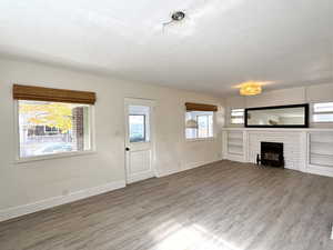 Unfurnished living room featuring wood finished floors, a fireplace, and a textured ceiling