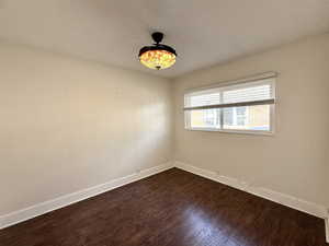 Unfurnished room with a textured ceiling and dark wood-style floors