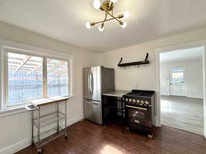 Kitchen featuring high end range, freestanding refrigerator, dark wood-type flooring, a chandelier, and a textured ceiling