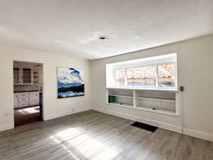Empty room featuring light wood-type flooring and a textured ceiling