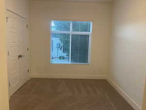 Empty room featuring dark colored carpet and baseboards