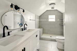 Full bathroom with a stall shower, double vanity, light tile patterned floors, lofted ceiling, and a textured ceiling