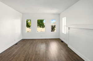 Spare room featuring dark wood-style floors and baseboards