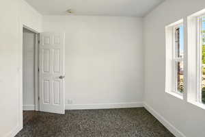 Unfurnished room featuring plenty of natural light and dark carpet