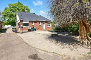 Rear view of house with brick siding, a chimney, entry steps, a patio area, and roof with shingles