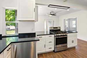 Kitchen featuring appliances with stainless steel finishes, a peninsula, recessed lighting, dark wood finished floors, and dark stone countertops