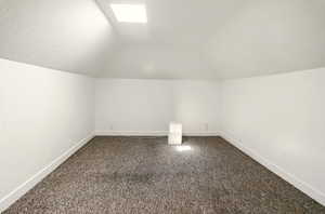 Bonus room featuring dark carpet and vaulted ceiling