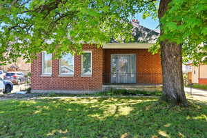Entrance to property featuring a yard and brick siding