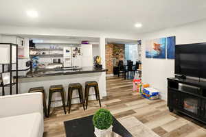 Bar with white appliances, light wood finished floors, recessed lighting, dark stone countertops, and backsplash