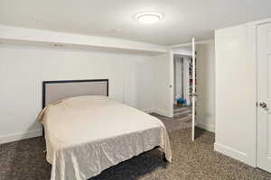 Carpeted bedroom with a textured ceiling and baseboards