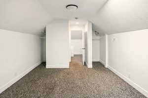 Bonus room featuring vaulted ceiling and dark colored carpet